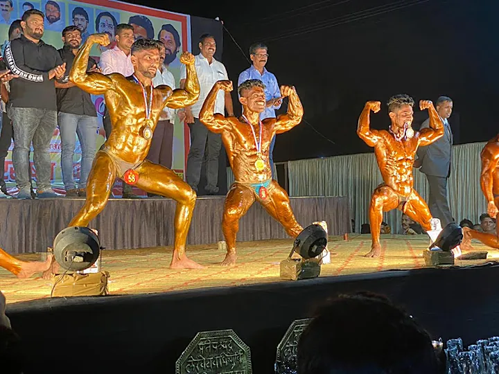 SPARTANS bodybuilders with medals posing on stage at a competition